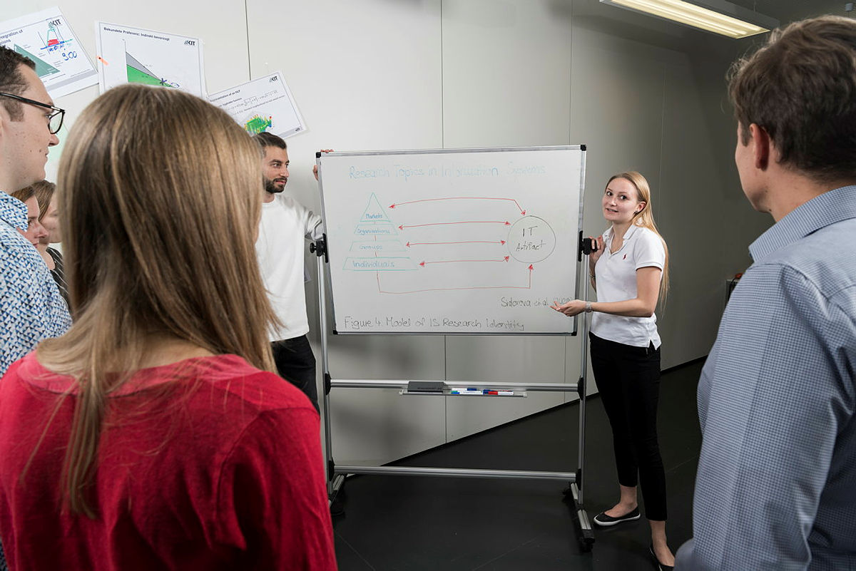 Studierende mit Blick auf eine Stellwand